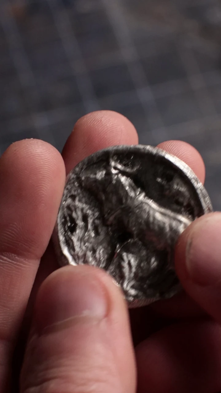 The real cast coin held in a hand during the original coin-making video