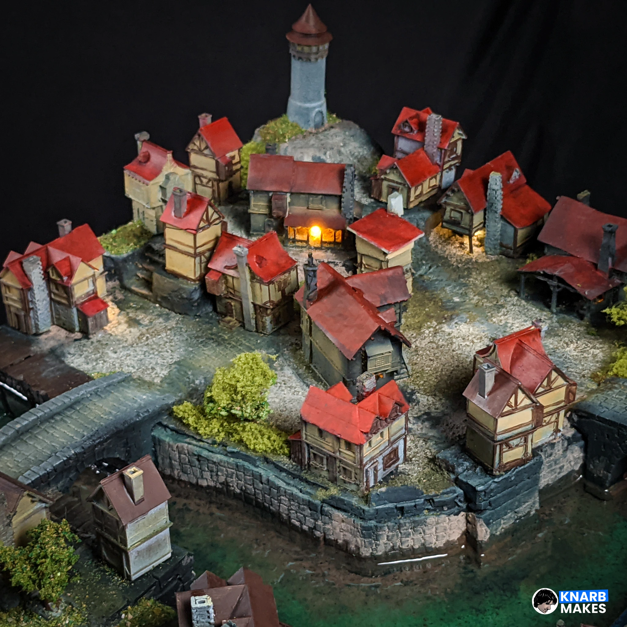 The original Knarb Makes painted medieval village with red roofs, glowing windows and a stone bridge